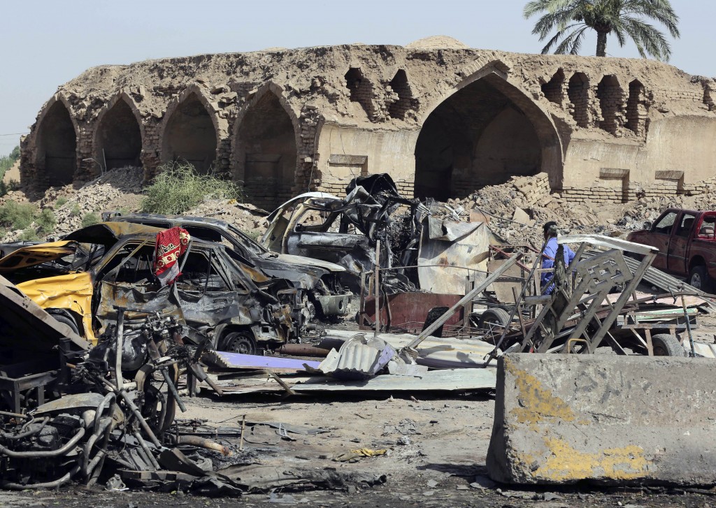 A civilian walks amid the debris from a deadly Friday night suicide car bombing at a busy market in Khan Beni Saad, about 20 miles (30 kilometers) northeast of Baghdad, Iraq, Saturday, July 18, 2015. The attack by the Islamic State group on a crowded marketplace in Iraq's eastern Diyala province has killed over 100 people, mostly-Shiite victims, including women and children, in one of the deadliest single attacks in the country in the past decade. (AP Photo/Karim Kadim)