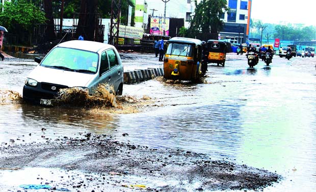 Hyderabad 16th August 2015; A car struggles to come out out of a gutter filled with rainwater on the road. Picture by P.Surendra