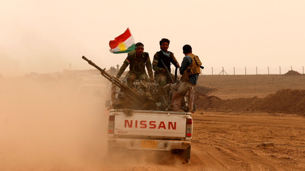 Kurdish Peshmerga fighters drive at the front line during a battle with Islamic State militants at Topzawa village near Bashiqa, near Mosul