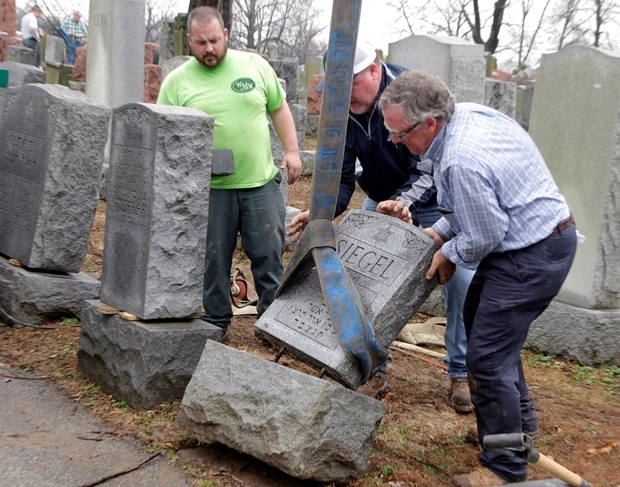 People view toppled Jewish headstones after a weekend vandalism attack on Chesed Shel Emeth Cemetery in University City